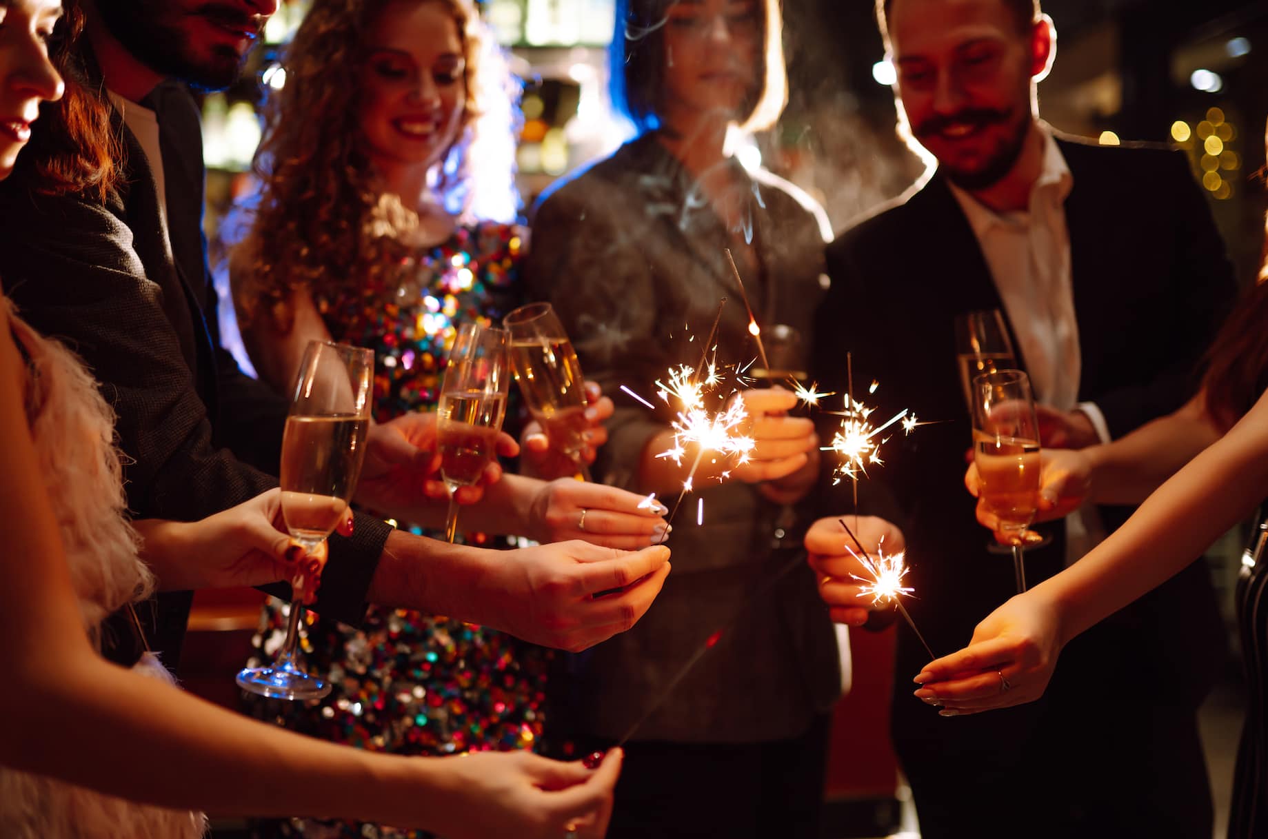 A group of people celebrating with sparklers and champagne at a festive gathering.
