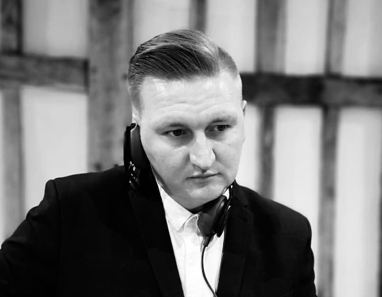 A man in a suit with headphones appears focused, set against a rustic background.