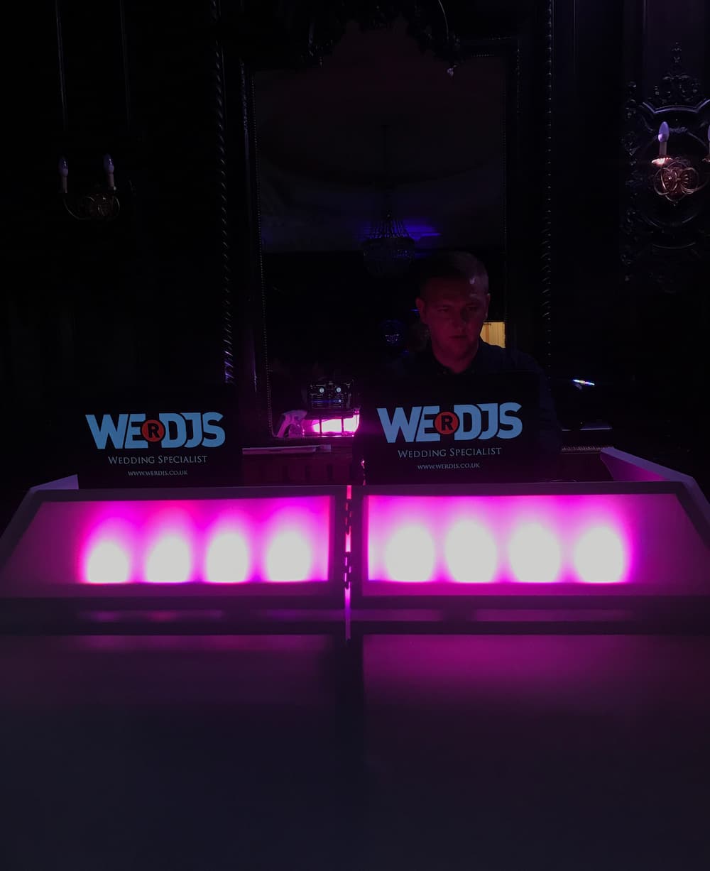 wedding dj at wedding booth with purple uplights