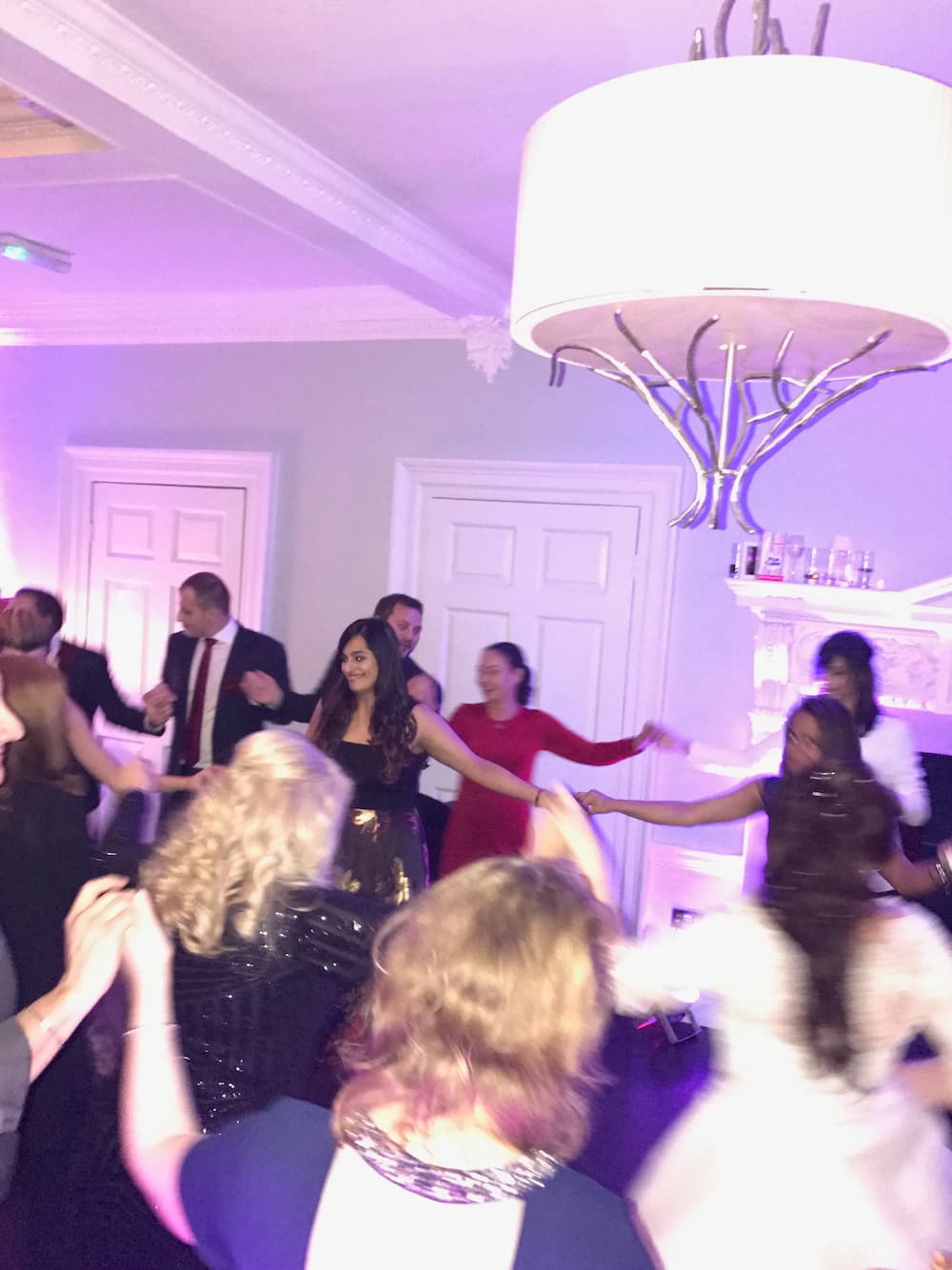 group at a wedding holdings hands and dancing